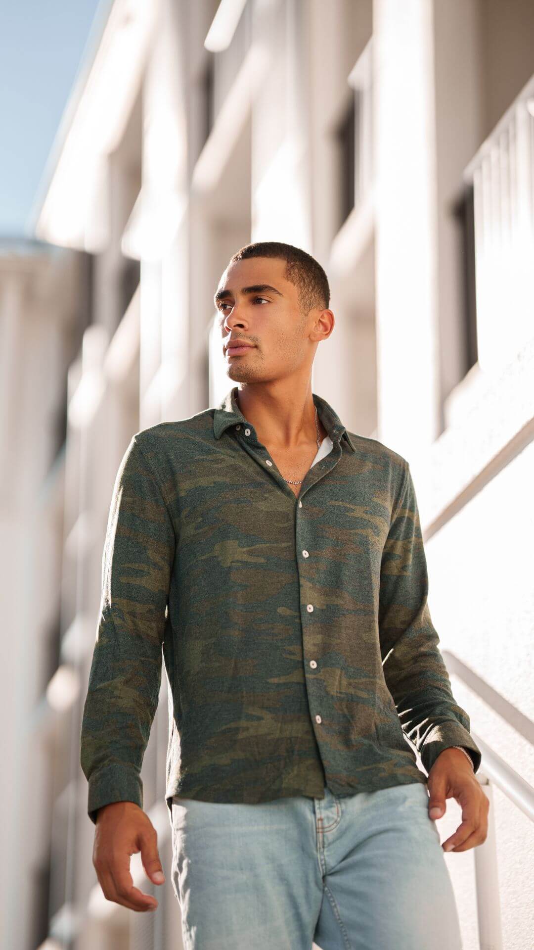 Model wearing a camoflouge long sleeved button up shirt